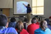 An instructor presenting slides in front of a group.