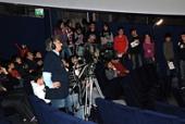 A crowd of people watching a broadcast and someone is recording it.